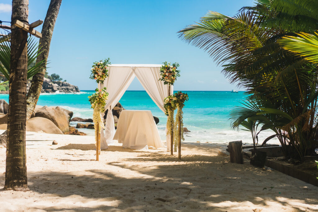 Weißer Strandpavillon geschmückt mit Blumen am Strand - für Hochzeit